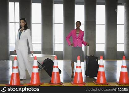 Two businesswomen standing with their luggage at a subway station