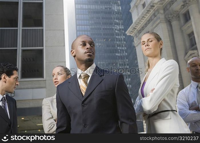 Two businesswomen standing with three businessmen