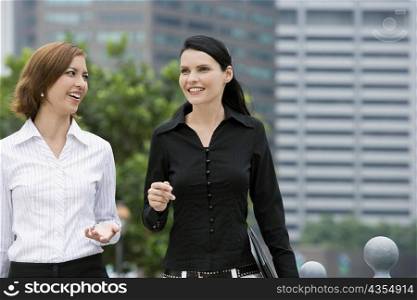 Two businesswomen walking together and smiling