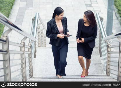 Two businesswomen walking up on stair and talking together. Business and work concept. Job and occupation concept.