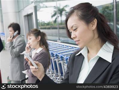 Two businesswomen with a businessman waiting at an airport lounge