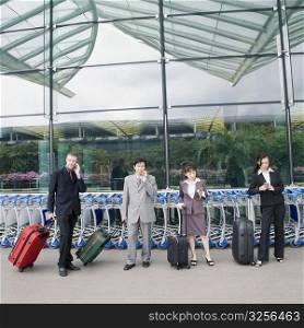 Two businesswomen with two businessmen waiting at an airport