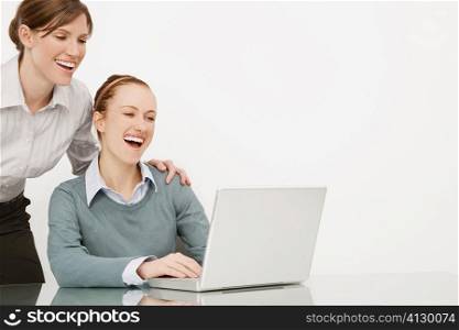 Two businesswomen working on a laptop and smiling