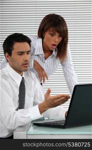 Two businessworkers shocked by laptop screen