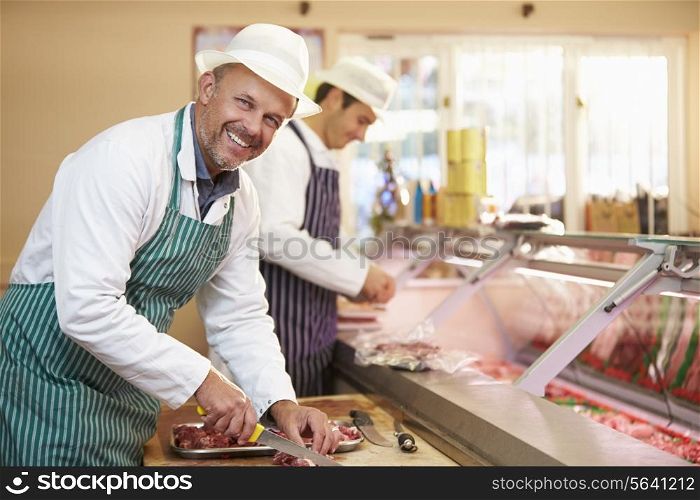 Two Butchers Preparing Meat In Shop