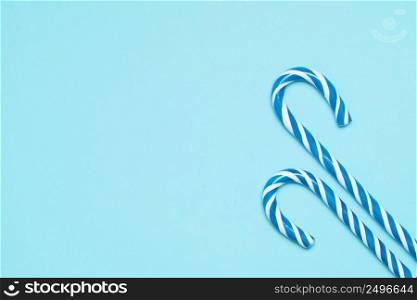 Two candy canes on blue background top view with copy space