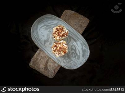 Two Caramel Pecanbon topped with decadent caramel frosting and pecans on ceramic tray with dark background. The concept of delicious food, Top view, Copy space, Selective Focus.