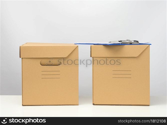 two cardboard boxes made of brown corrugated cardboard are on a white table, moving, goods delivery