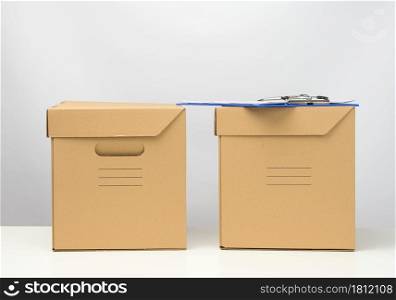 two cardboard boxes made of brown corrugated cardboard are on a white table, moving, goods delivery