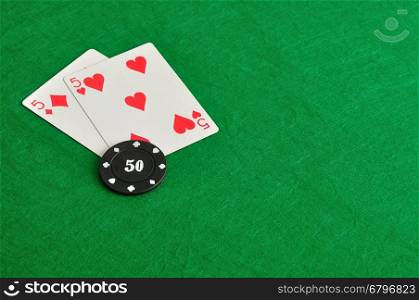 Two cards with a poker chip on a green background