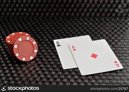 Two cards with red poker chips on a black background