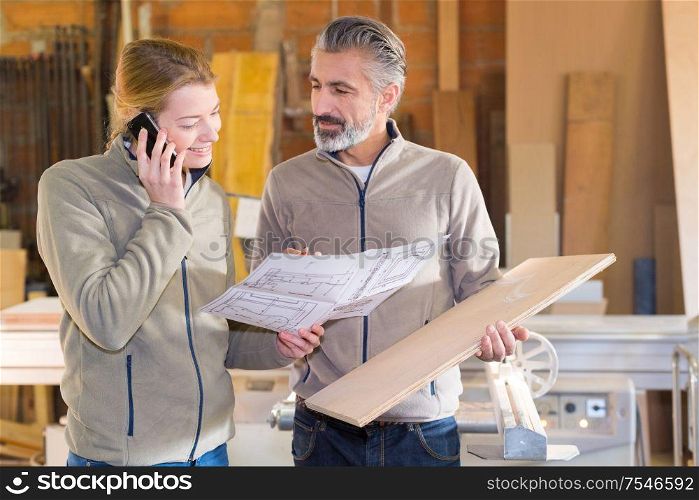 two carpenters with drawings in workshop