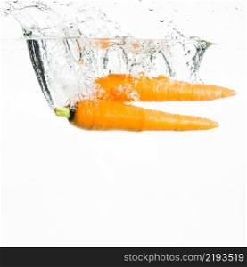 two carrots splashing water against white background