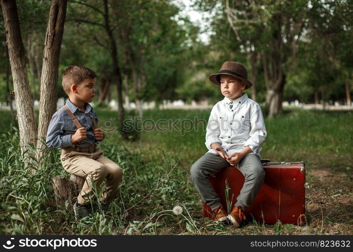 two Caucasian boy brothers in vintage clothes sit opposite each other and watch