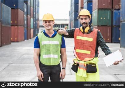 Two caucasian engineers are working and control containers loading at site for shipping. Engineering and Logistics Concept.