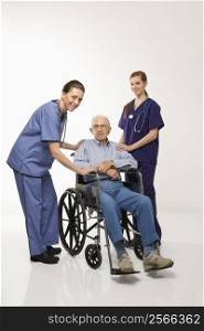 Two Caucasian females wearing scrubs with elderly Caucasian male in wheelchair.