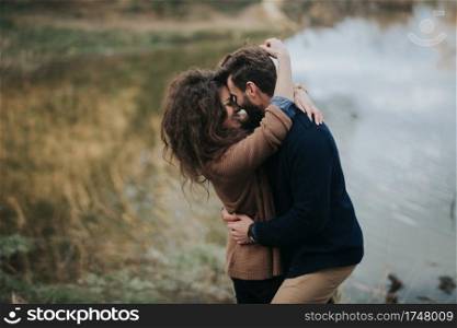 two caucasian lovers near the lake. Young couple is hugging on autumn day outdoors. A bearded man and curly woman in love. Valentine’s Day. Concept of love and family.. two caucasian lovers near the lake. Young couple is hugging on autumn day outdoors. A bearded man and curly woman in love. Valentine’s Day. Concept of love and family