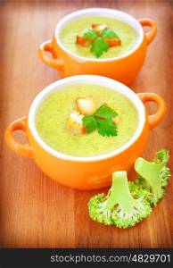 Two ceramic bowl with tasty vegetarian creamy soup on wooden table, fresh green broccoli piece, healthy eating, diet concept