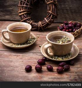 Two ceramic cups brewed tea with rosehip and chamomile amid bundles of licorice root. Two ceramic cups brewed tea