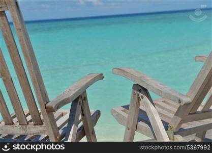 Two chairs beds in forest on tropical beach with blue ocean in background