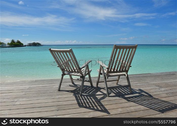 Two chairs beds in forest on tropical beach with blue ocean in background