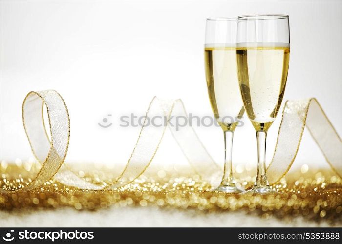 Two champagne flutes and decoration on gold shiny background