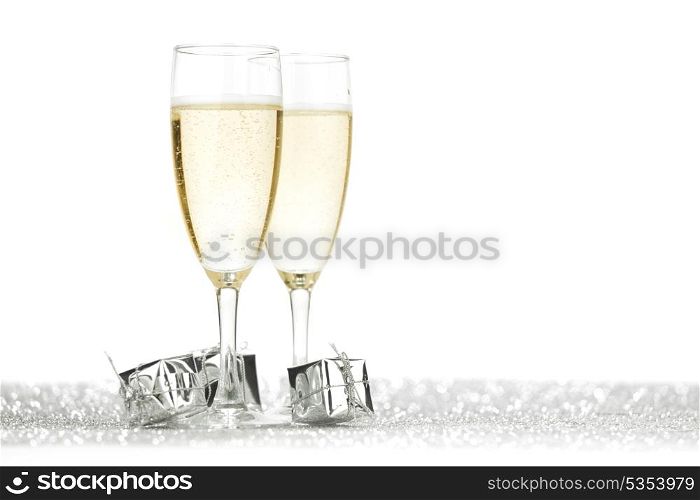 Two champagne flutes and gifts on shiny background