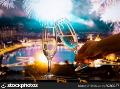 two champagne glasses against fireworks in the city New Year&rsquo;s eve celebrations