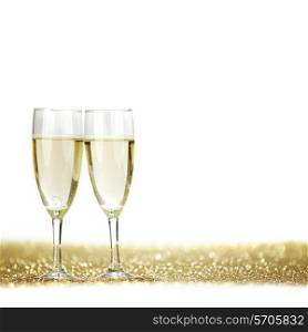 Two champagne glasses and golden shiny glitters isolated on white background