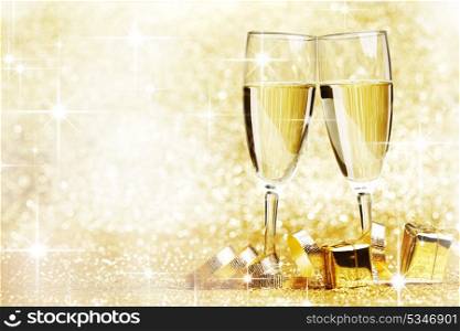 Two champagne glasses, gifts and decoration on golden background