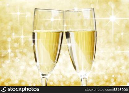 Two champagne glasses on golden shiny stars background