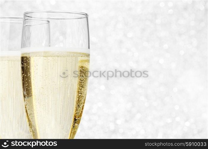 Two champagne glasses on silver bokeh background
