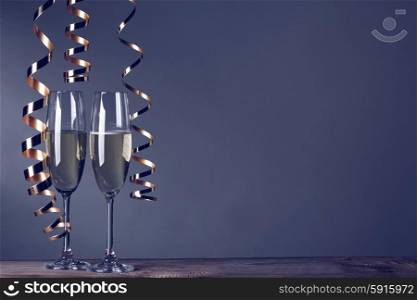 Two champagne glasses . Two champagne glasses and curly ribbons on dark background