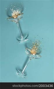 Two champagne glasses with splash of confetti over creative background. Overhead view, Christmas and New Year concept