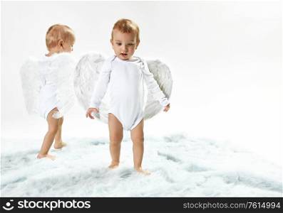 Two cheerful baby angels walking on the soft carpet