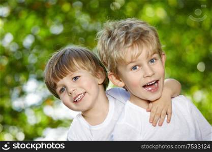 Two cheerful boys embrace in a summer garden