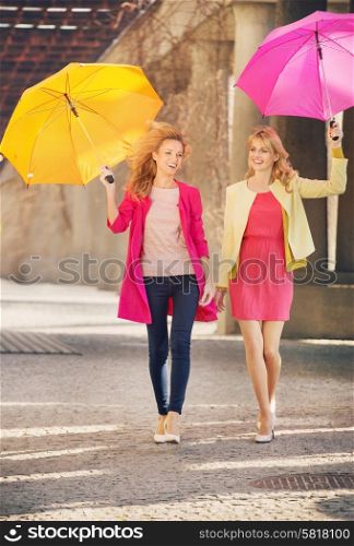 Two cheerful girlfriends walking during windy day