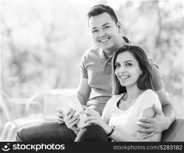 Two cheerful lovers sitting on the couch and huging while using tablet