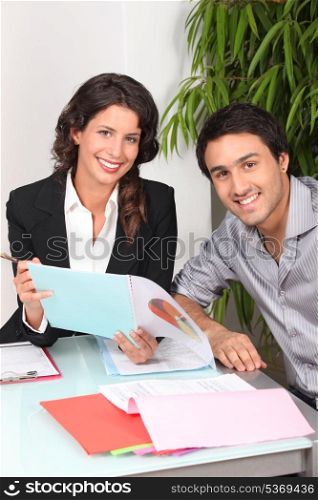 Two cheerful workers looking at financial information