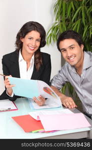 Two cheerful workers looking at financial information