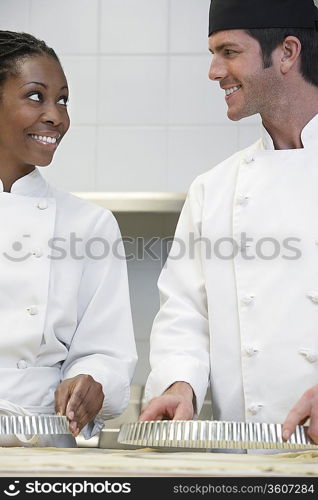 Two chefs preparing food in kitchen, smiling