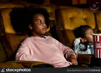 Two children african and asian having fun and enjoy watching movie in cinema