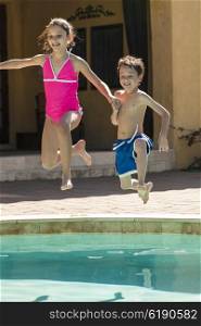 Two children boy and girl laughing having fun jumping into swimming pool
