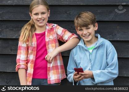 Two children boy and girl smiling and using cell phone