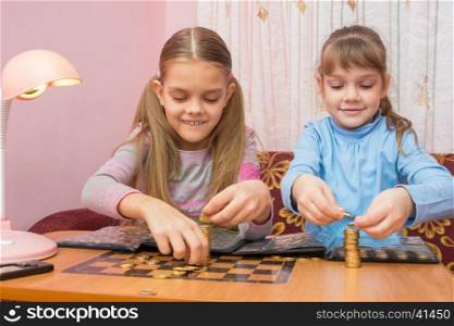 Two children build towers of coins