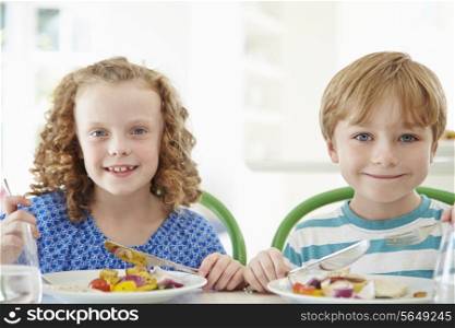 Two Children Eating Meal At Home Together