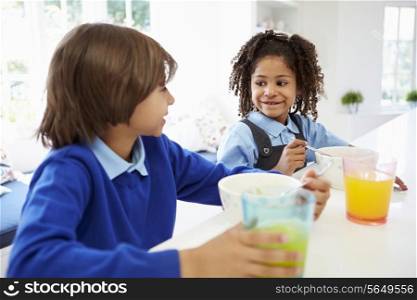 Two Children Having Breakfast Before School In Kitchen