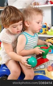 two children in playroom on toy scooter