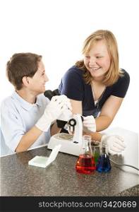 Two children in science class having fun looking through a microscope. White background.