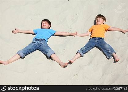 Two children lying nearby on sand